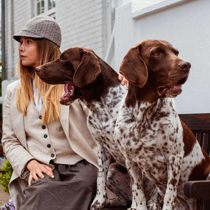 Women sitting with her two dogs waiting to be fed essentials dog food